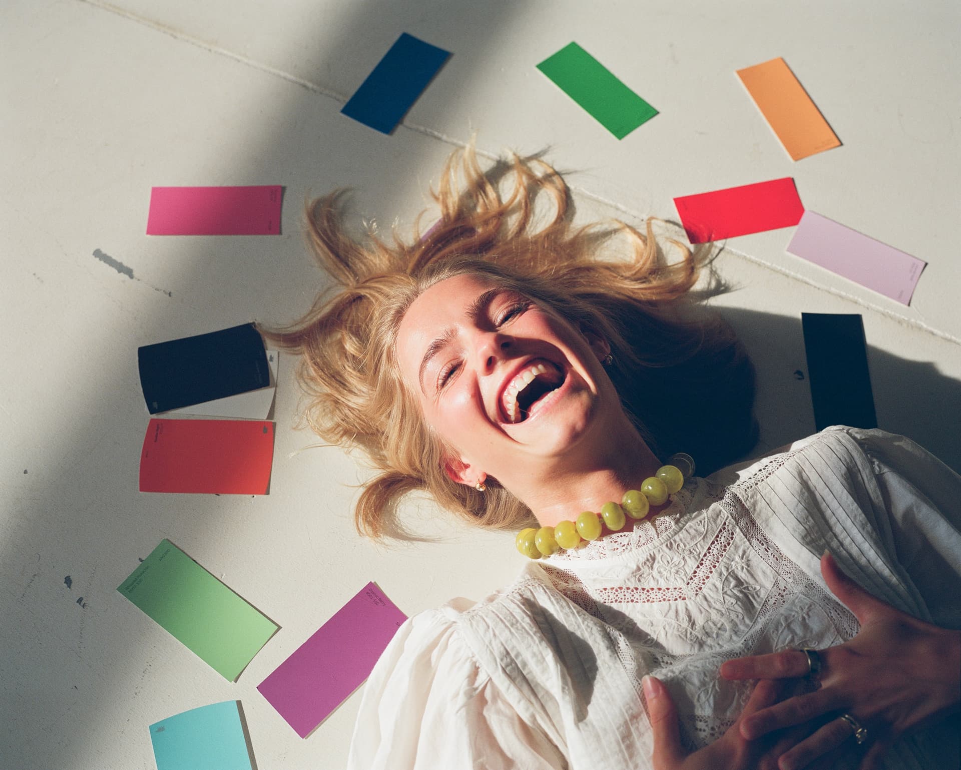 Woman laughing among scattered paint swatches